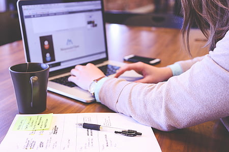 woman using MacBook Pro beside mug and smartphone thumbnail