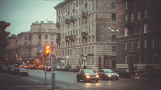 two vehicles passing through road beside buildings thumbnail