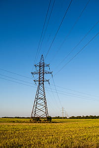 brown electric tower on grass field thumbnail