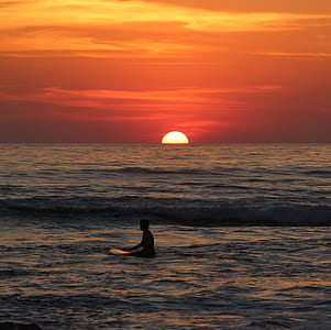 man on surfing board floating on water at golden hour thumbnail