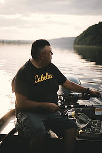 man sitting on canoe sailing on body of water thumbnail