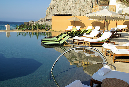 empty white and green padded loungers facing body of water thumbnail