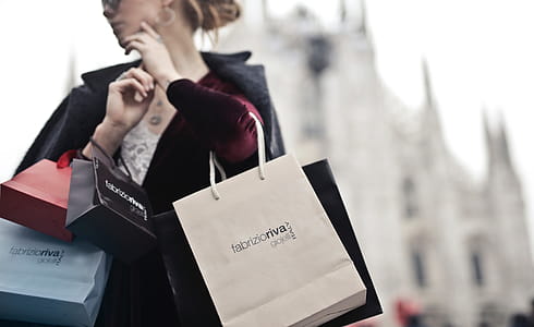 A young blond woman wearing a satin dress holding shopping bags in her hands thumbnail