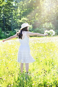 woman wearing white spaghetti strap dress surrounded by grass during daytime thumbnail