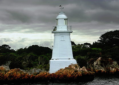 white concrete lighthouse near body of water at daytime thumbnail