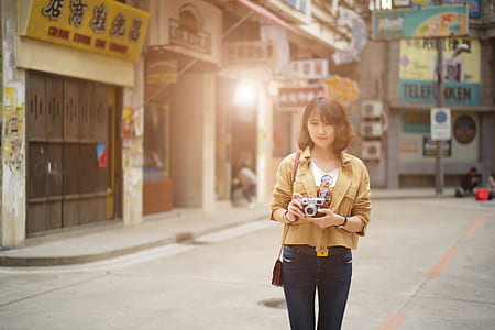 woman walking on the road holding camera thumbnail