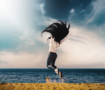 woman in white shirt and blue jeans jumping near body if water thumbnail