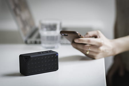 black Bluetooth speaker on white table thumbnail
