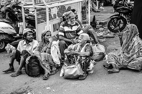 women and men sitting on ground near white metal gate thumbnail