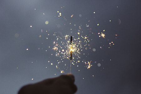 person holding sparkle firecracker in auto focus photography thumbnail