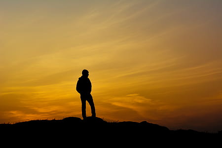silhouette photo of man standing on ground during daytime thumbnail