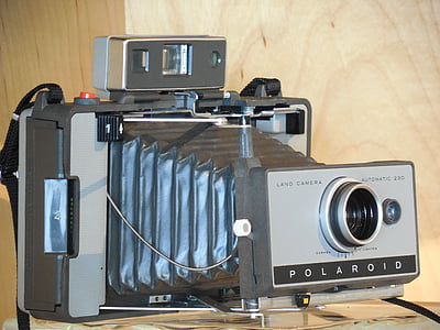 vintage gray Polaroid folding camera on brown surface thumbnail