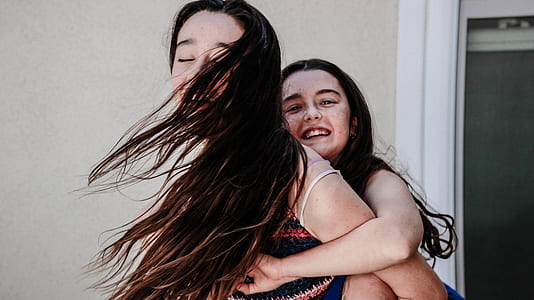 girl hugging woman near white concrete wall thumbnail