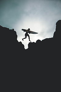 silhouette of person carrying surfboard thumbnail