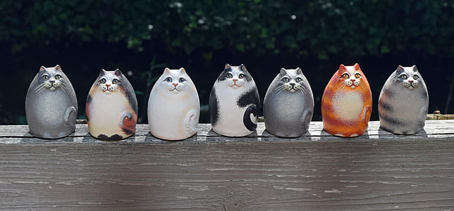 seven assorted-color cat figurines on top of brown wooden surface thumbnail