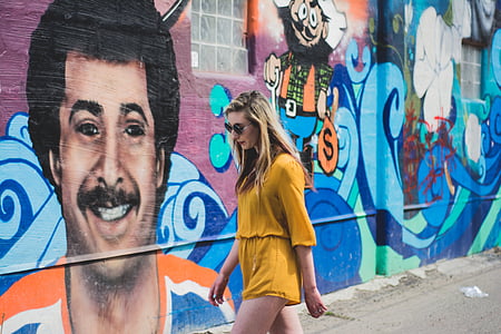 woman walking beside wall with graffiti thumbnail