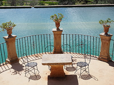 brown concrete table with 4-chairs beside body of water during daytime thumbnail
