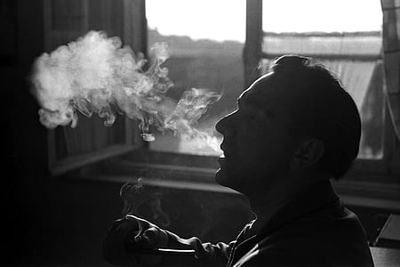 man smoking near clear glass window thumbnail