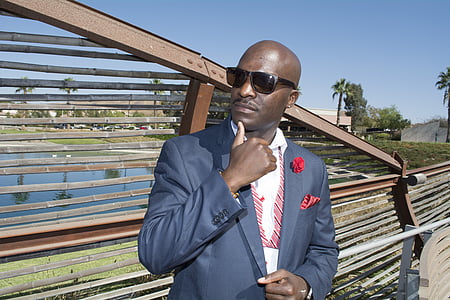 man wearing gray blazer standing near brown wooden fence at daytime thumbnail
