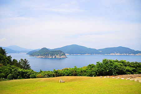 green grass field and body of water under blue sky thumbnail
