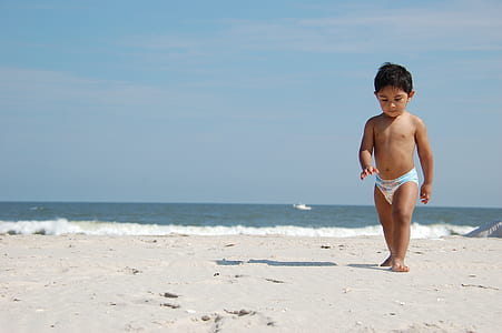 boy wearing disposable diaper walking near sand beside seashore during daytime thumbnail