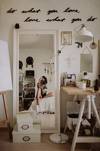woman sits on bed taking mirror photo thumbnail