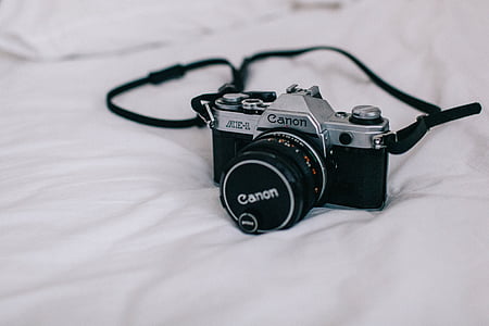 black Canon DSLR camera on the white textile thumbnail