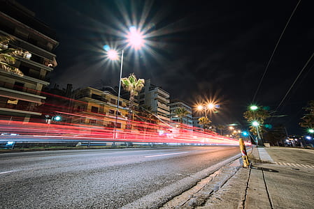 timelapse photography of vehicle passing on road near buildings thumbnail
