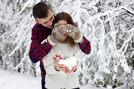 man surprising woman holding white snow at daytime thumbnail