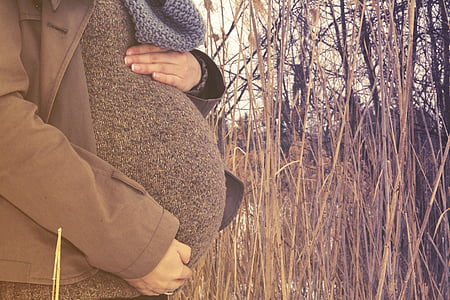 woman holding her baby bump near green grass thumbnail