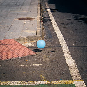 blue balloon above brown concrete pavement with shadow at daytime thumbnail