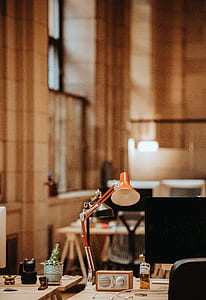 selective focus of orange desk lamp and flat screen monitor in room thumbnail