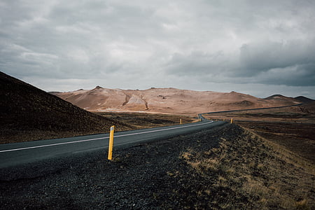black asphalt road surrounded by mountains thumbnail
