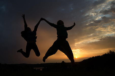 two person jumping while holding each other at daytime thumbnail