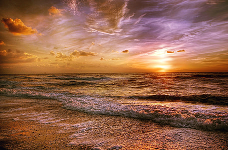 brown seashore and body of water waves under brown clouds and gray sky thumbnail