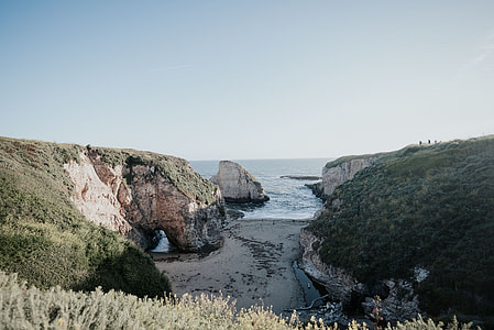 body of water between two mountains under blue sky thumbnail