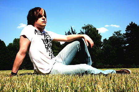 man sitting on grass surrounded by trees thumbnail