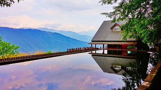 brown house on body of water and mountain at distance during daytime thumbnail