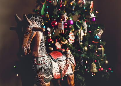 shallow focus photography of wooden ride-on horse beside Christmas tree thumbnail