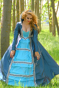 selective focus photography of woman wearing blue ball gown standing on green grass field thumbnail