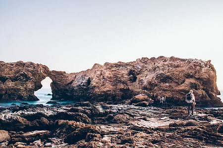 person standing near rock formation during daytime thumbnail