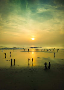 people standing on seashore during golden hour thumbnail
