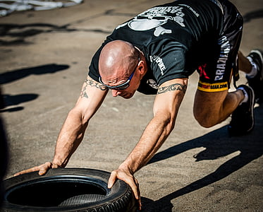 man wearing black shirt and shorts pushing tire thumbnail