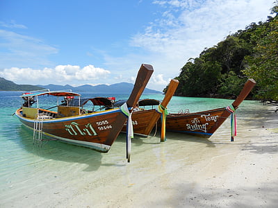 three brown wooden boats near trees thumbnail