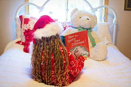 girl seating on mattress while reading book thumbnail