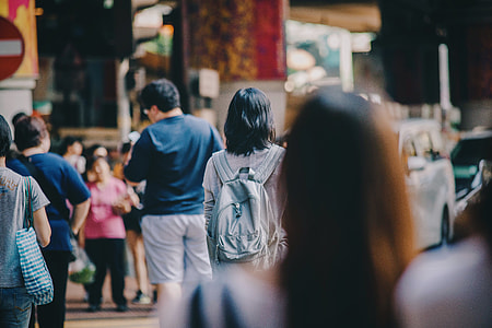 woman in gray backpack walking on road thumbnail