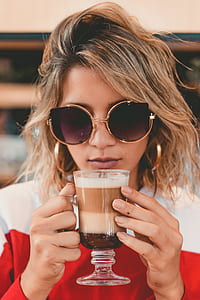 woman in red and white long-sleeved shirt holding footed glass with cappuccino thumbnail