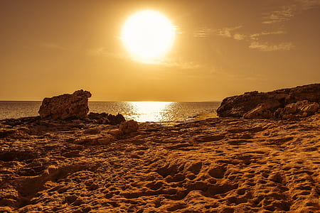 rock formation beside body of water during sunset thumbnail