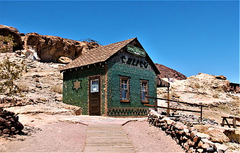 green and brown house near cliff thumbnail