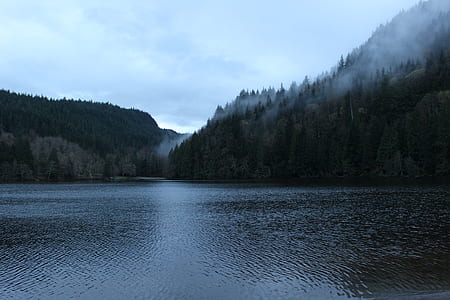 large body of water near mountain under gray sky during daytime thumbnail
